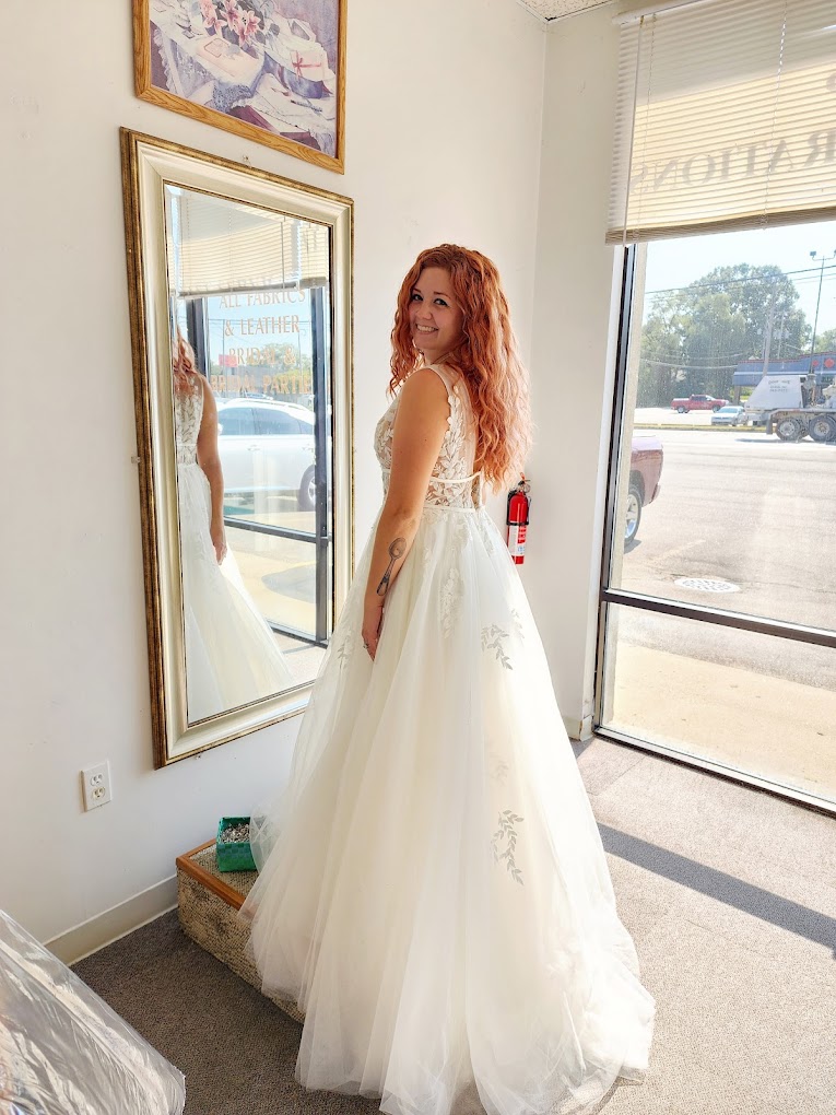 Customer in a lace wedding gown checking the fit at the shop mirror